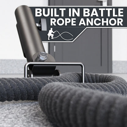 Black landmine platform with cylindrical steel sleeve and built-in battle rope anchor point, shown with gray battle rope coiled on gym floor.