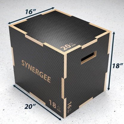 Black and wood plyo box with textured rubber top surface, labeled "SYNERGEE" with dimensions marked as 16" width, 18" height, and 20" depth. Top surface shows 20 lb capacity marking.