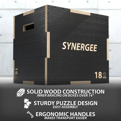 Black textured plyo box with light wood frame edges and handles, labeled "SYNERGEE" and marked "18 inch" height, shown against white brick background.