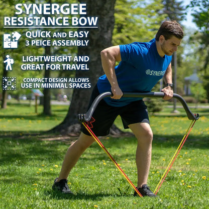 Man performing a rowing motion with a black curved resistance bow connected to red and yellow resistance bands in an outdoor park setting.