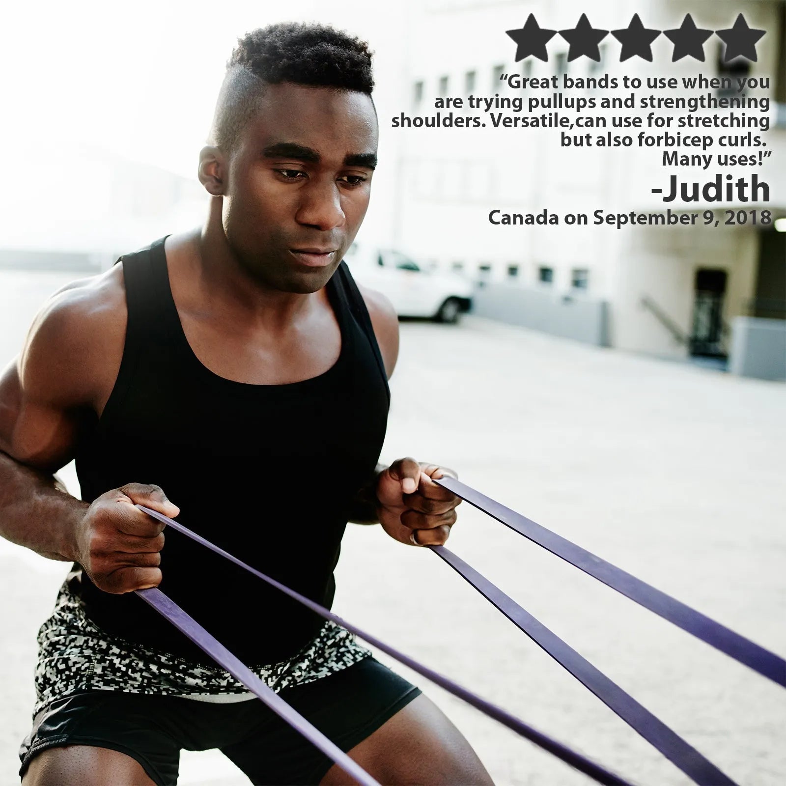 Man in black tank top holding purple resistance bands taut in front of him outdoors, demonstrating the stretchy bands in use.