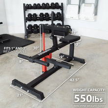 Black seated calf raise machine with red vertical post, padded backrest and footplate, labeled with dimensions and 550 lbs weight capacity. Dumbbell rack with hexagonal weights visible in background.