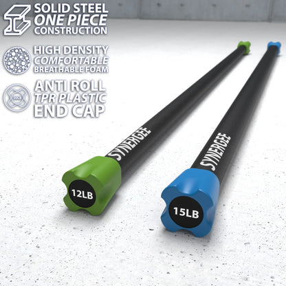 Two Synergee weighted workout bars with solid steel construction and colored end caps on a speckled gray surface. The green bar is labeled 12LB and the blue bar is labeled 15LB.