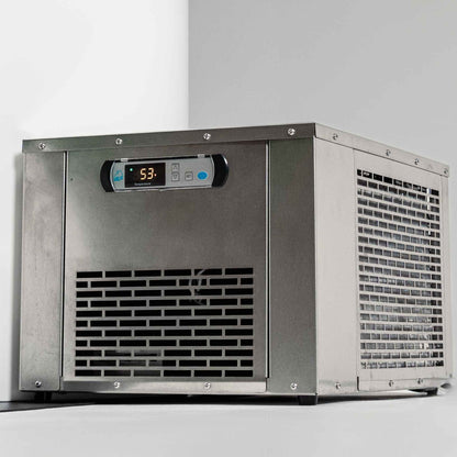 A stainless steel ice maker machine with a digital display showing a temperature of 53 degrees. The machine features a vented front and side, positioned against a white wall.