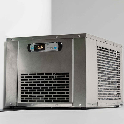 A stainless steel ice maker machine with a digital display showing a temperature of 53 degrees, placed against a light-colored wall.