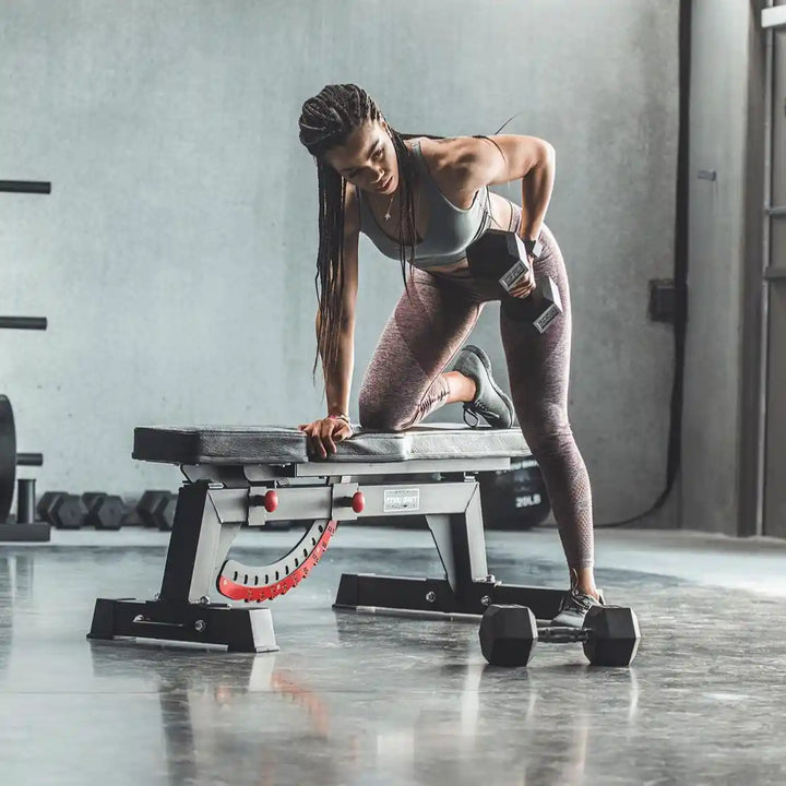 Woman exercising on a Tru Grit Fitness flat weight bench in a gym setting