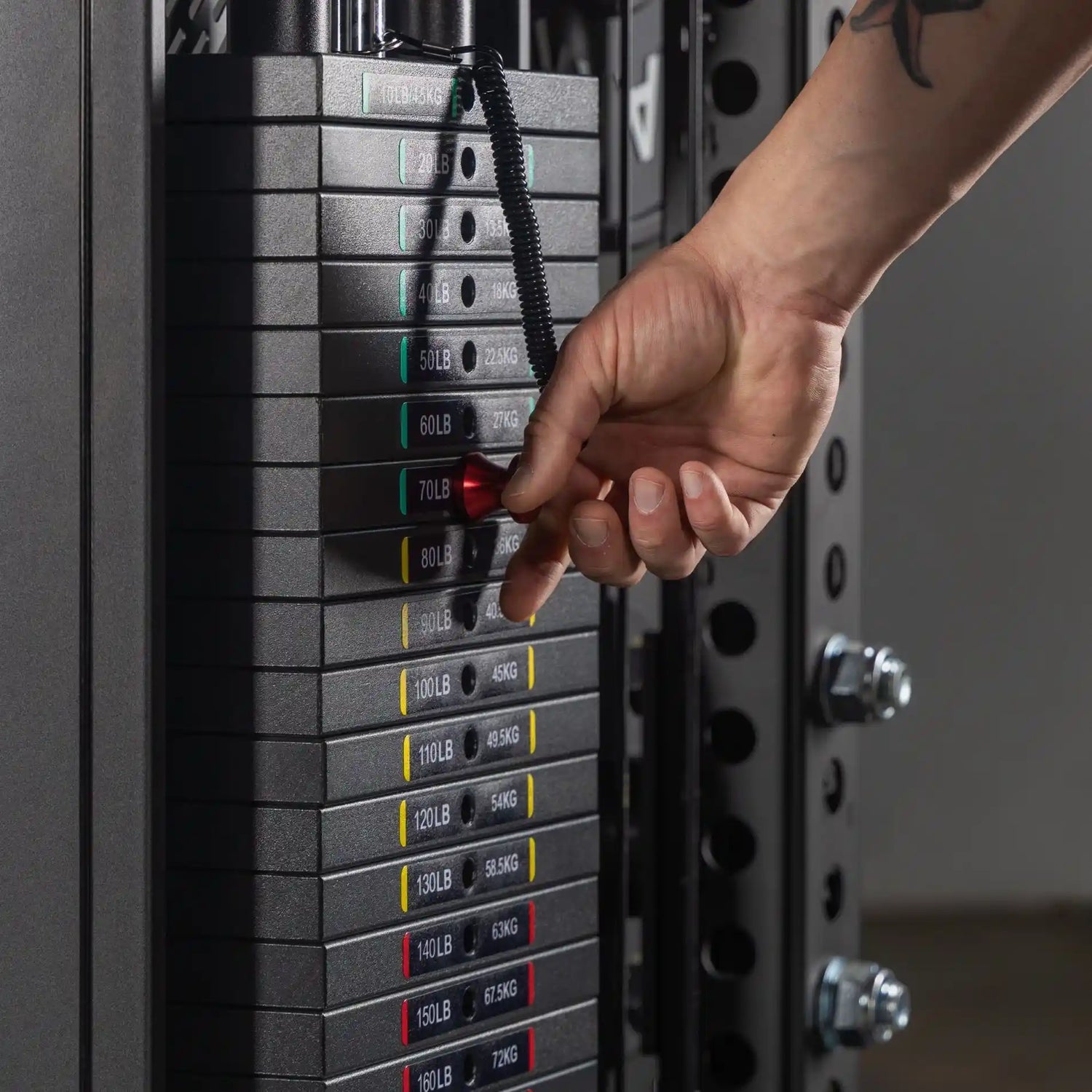 Hand adjusting weight plates on a XMARK fitness weightlifting machine